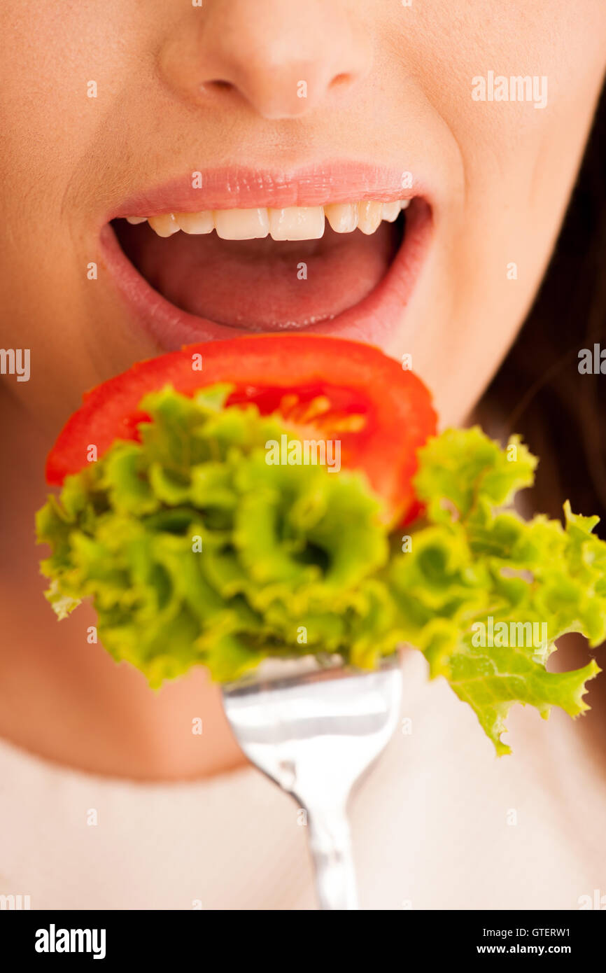 Mangiare sano - donna mangia una ciotola di insalata greca isolate su sfondo bianco - Pasto vegetariano Foto Stock