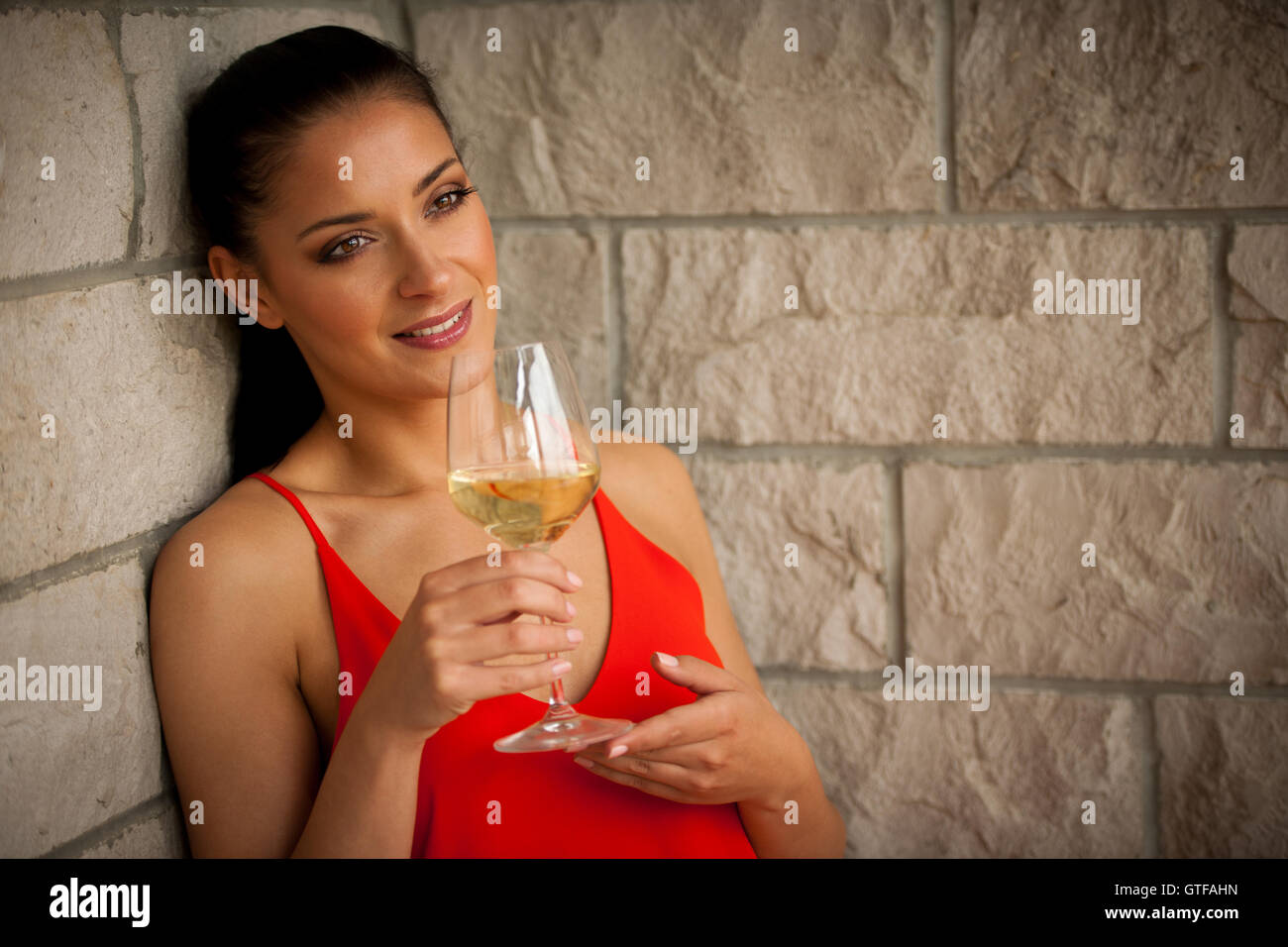 Bella donna in rosso abiti estivi con un bicchiere di vino bianco Foto Stock