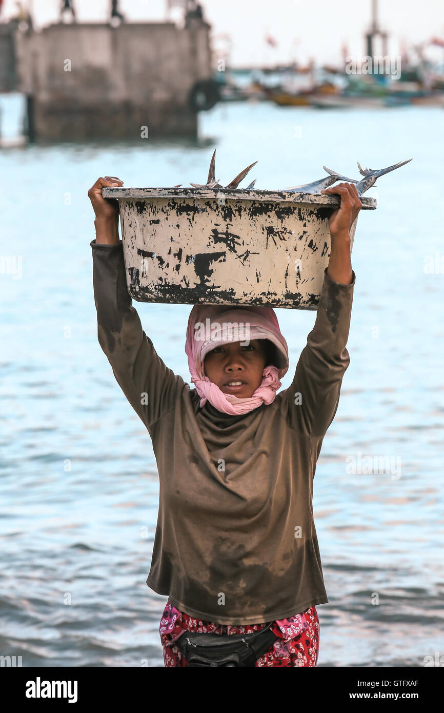 BALI, Indonesia - 13 agosto 2016 : pescivendolo Balinese trasportare pesci nel bacino del mercato mattutino in Kedonganan - Passer Ikan, Jimbaran Beach Foto Stock