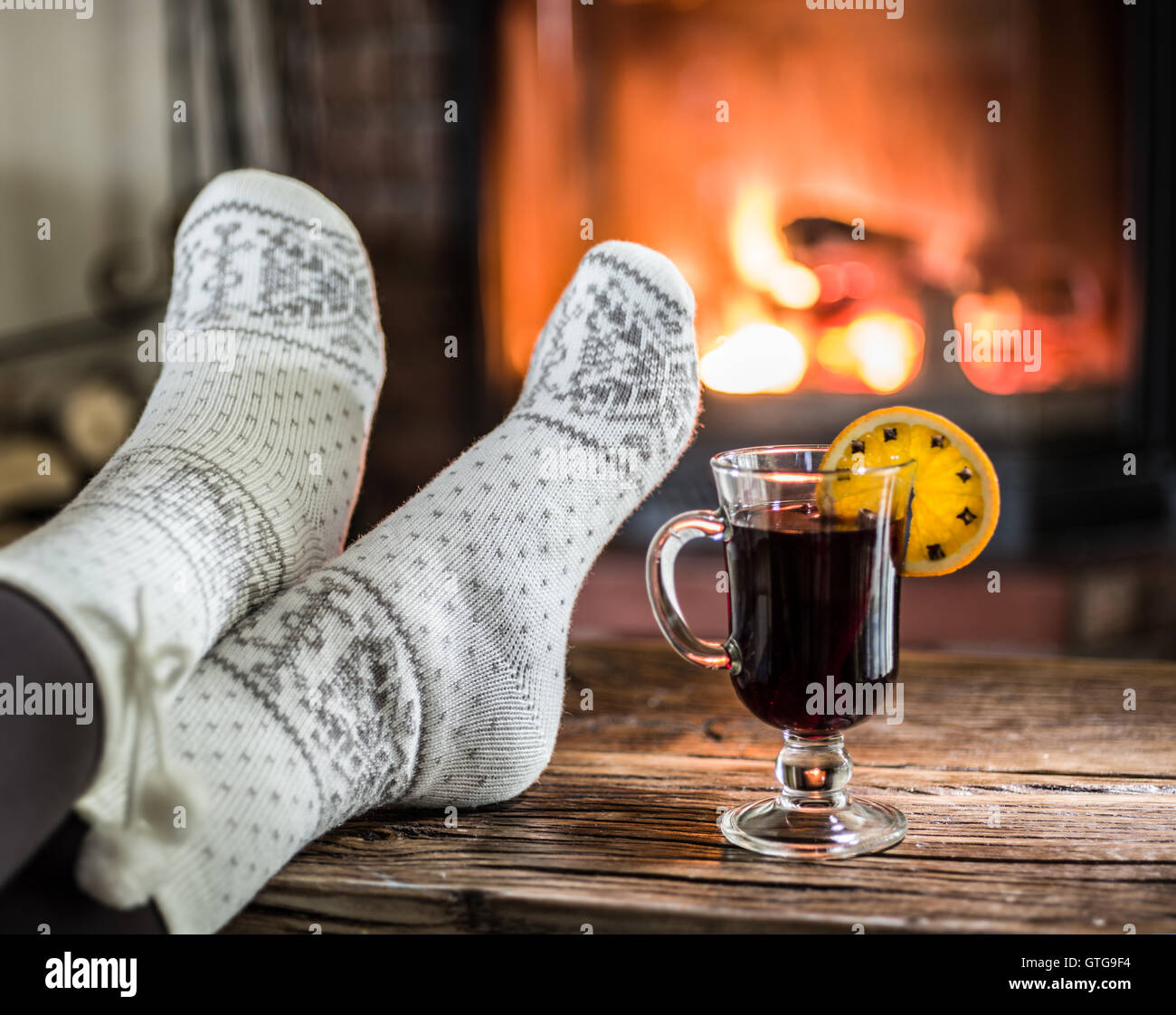 Riscaldamento e rilassarsi vicino al camino. Donna piedi vicino alla tazza di vino caldo nella parte anteriore del fuoco. Foto Stock