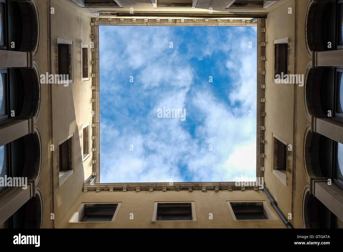 Cielo blu e nuvole bianche visto dall'interno di un cortile quadrato, Venezia Italia Foto Stock