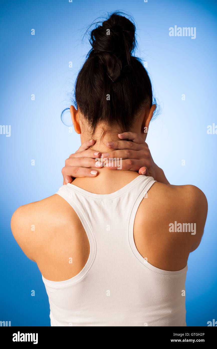Donna con il dolore nel suo collo su sfondo blu Foto Stock