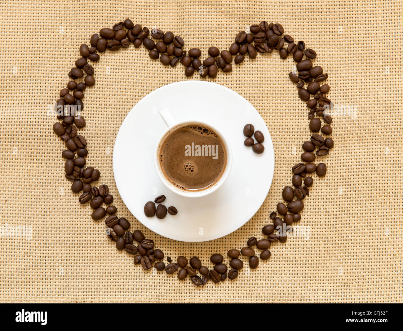 I chicchi di caffè nella forma del simbolo del cuore e una tazza di caffè nero caffè. Concetto di mi piace il caffè. Foto Stock