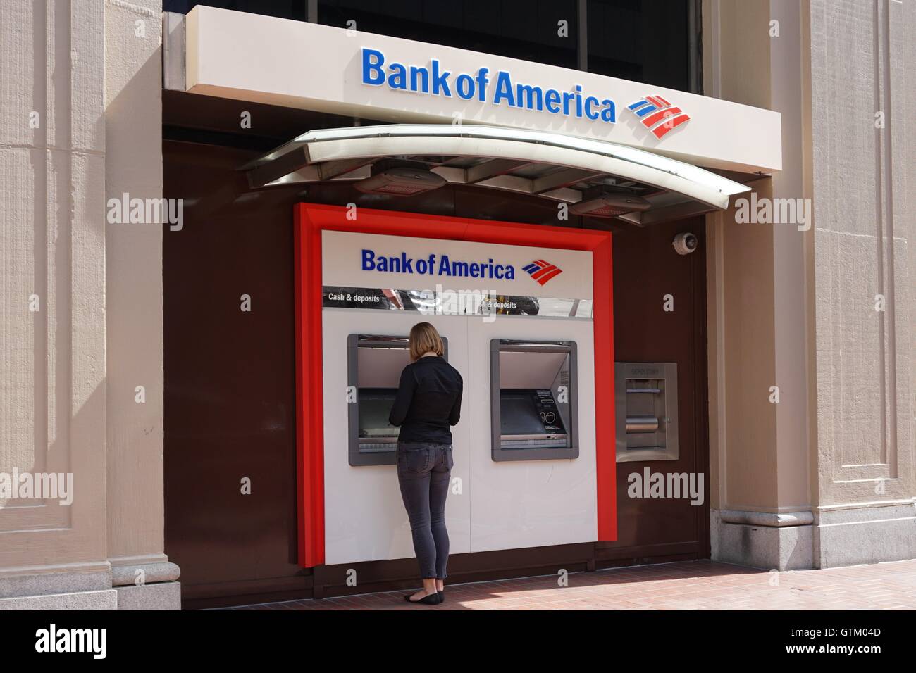 Una donna si trova di fronte a una banca di America macchina ATM, Bank of America branch storefront, San Francisco, California Foto Stock
