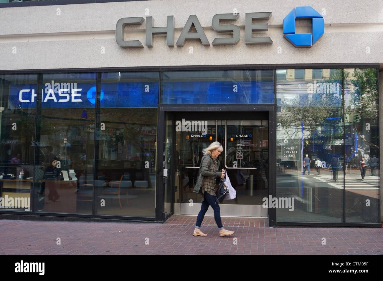 Una donna cammina da un Chase Bank storefront branch Foto Stock
