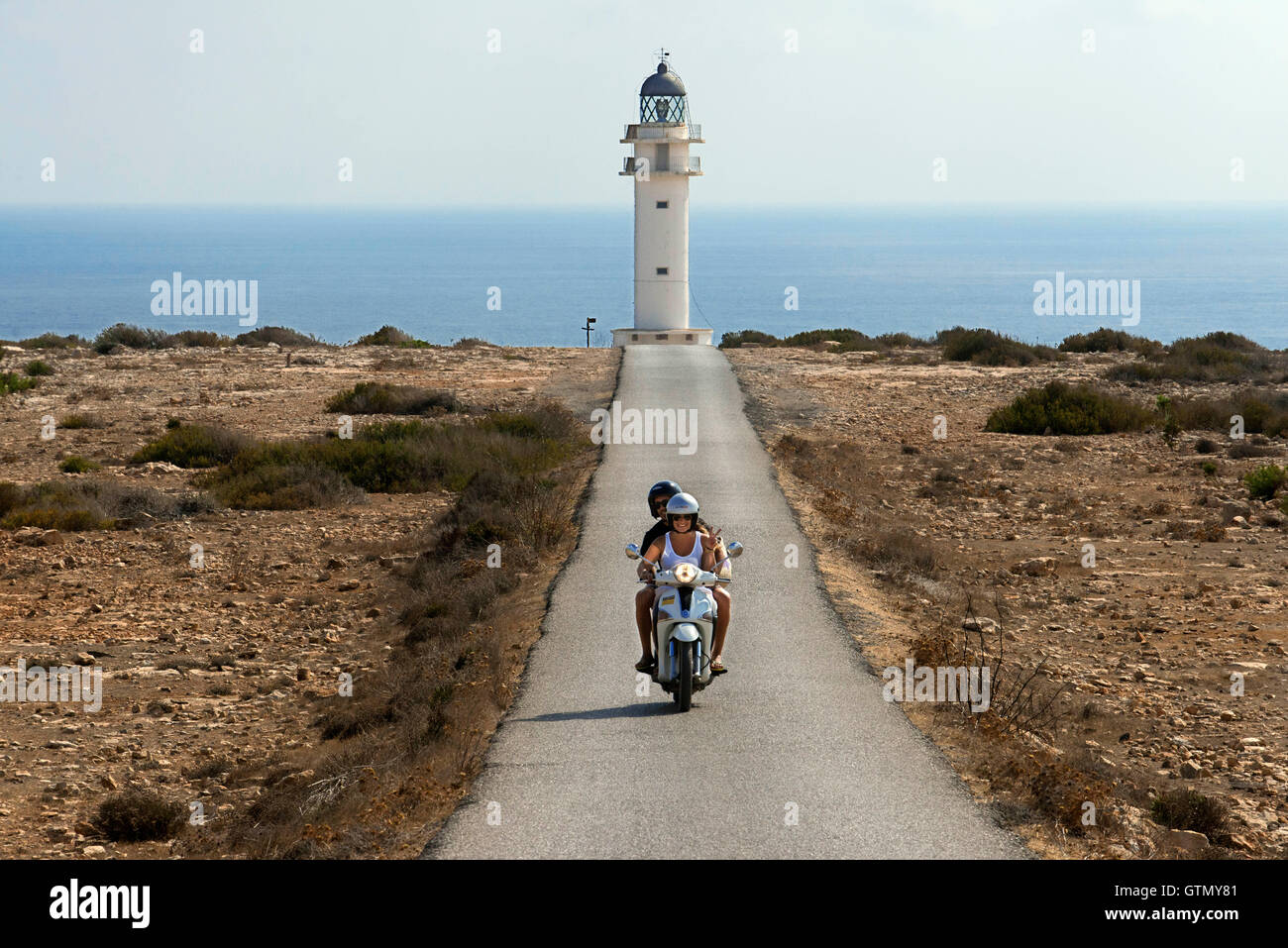Due giovani motociclisti su una lunga strada di Es Cap de Barbaria faro, a Formentera, isole Baleari. Spagna. Barbaria cape fo Foto Stock