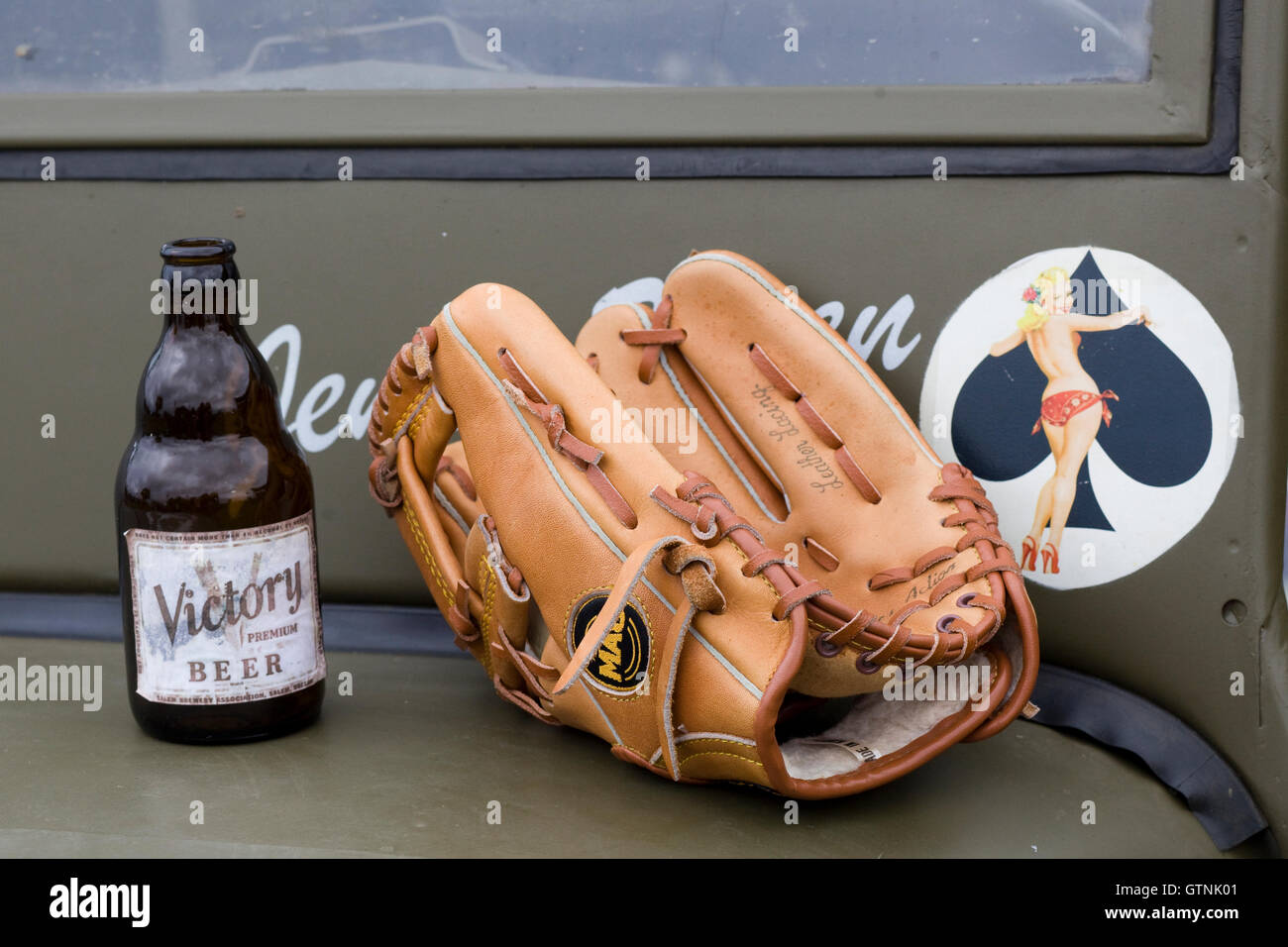 Bottiglia di birra Vittoria e Guanto baseball sul cofano del motore di un militare di American Jeep Foto Stock
