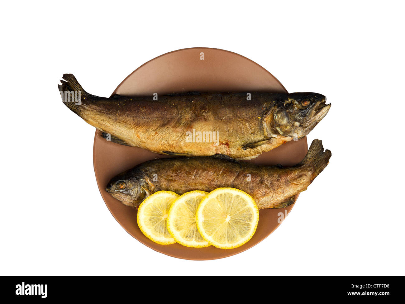 Sul tavolo di legno è una piastra con due pesci cotti al forno trote con il limone Foto Stock