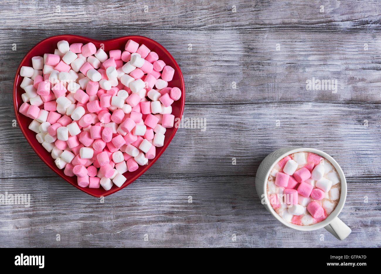 Su un nero tavolo in legno in stile rustico cuore rosso a forma di lastra con marshmallows, vi è uno spazio vuoto per il tuo testo, congrat Foto Stock