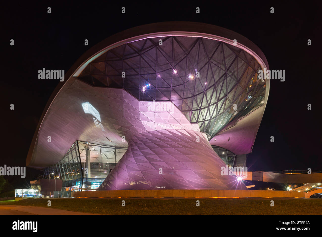 Viola e rosa facciata illuminata della BMW World building a Monaco di notte,Baviera,Germania Foto Stock