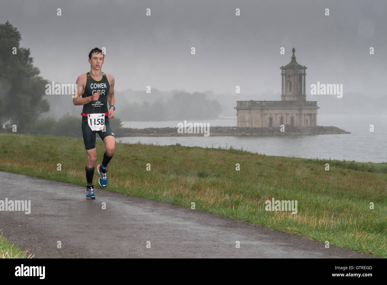 Rutland acqua, UK. Il 10 settembre, 2016. William Cowen, con il miglior singolo tempo complessivo di 3 ore e 45 minuti, costeggia il parzialmente sommerso chiesa di Normanton a Rutland serbatoio di acqua in un giorno di pioggia durante il triathlon vitruviano (comprendente un 1900 metri nuotata, 85 chilometri in bicicletta e 21 chilometri eseguire) su10 settembre 2016. Credito: miscellanea/Alamy Live News Foto Stock