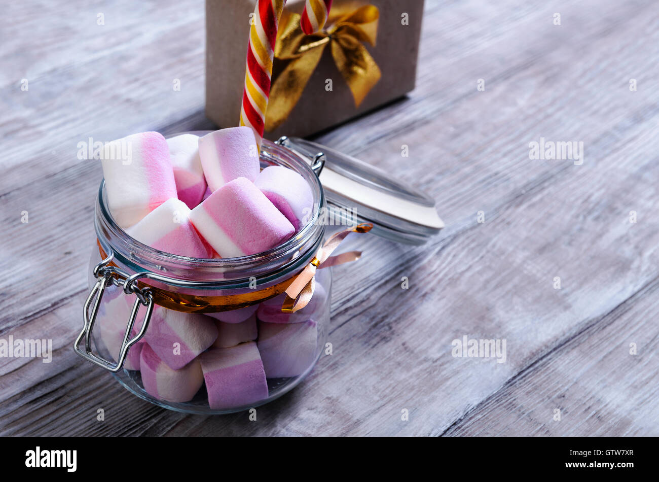 Su un bianco shabby tavolo in legno vaso di vetro con un dispositivo di chiusura con una marshmallow e candy cane Foto Stock