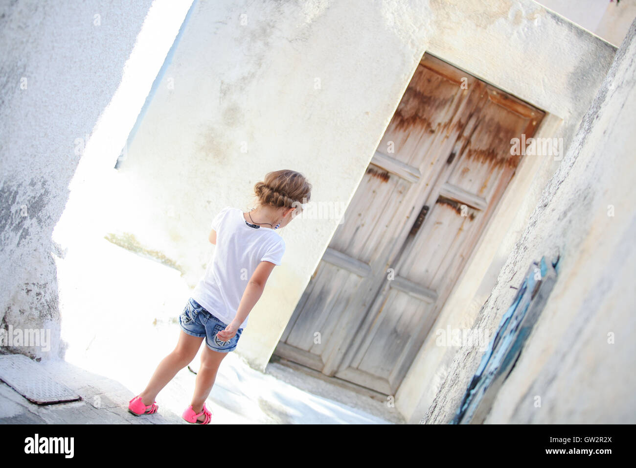 Adorabile ragazza camminare da solo in strade strette del villaggio Emporio sull'isola di Santorini, Grecia Foto Stock