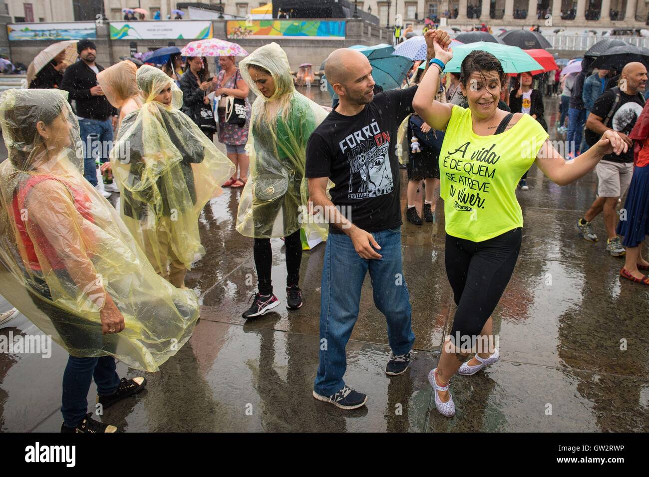 La gente ballare sotto la pioggia in Trafalgar Square, Londra, durante il giorno Brasile 2016, una celebrazione del Rio 2016 Giochi olimpici e paraolimpici e la cultura brasiliana. Foto Stock