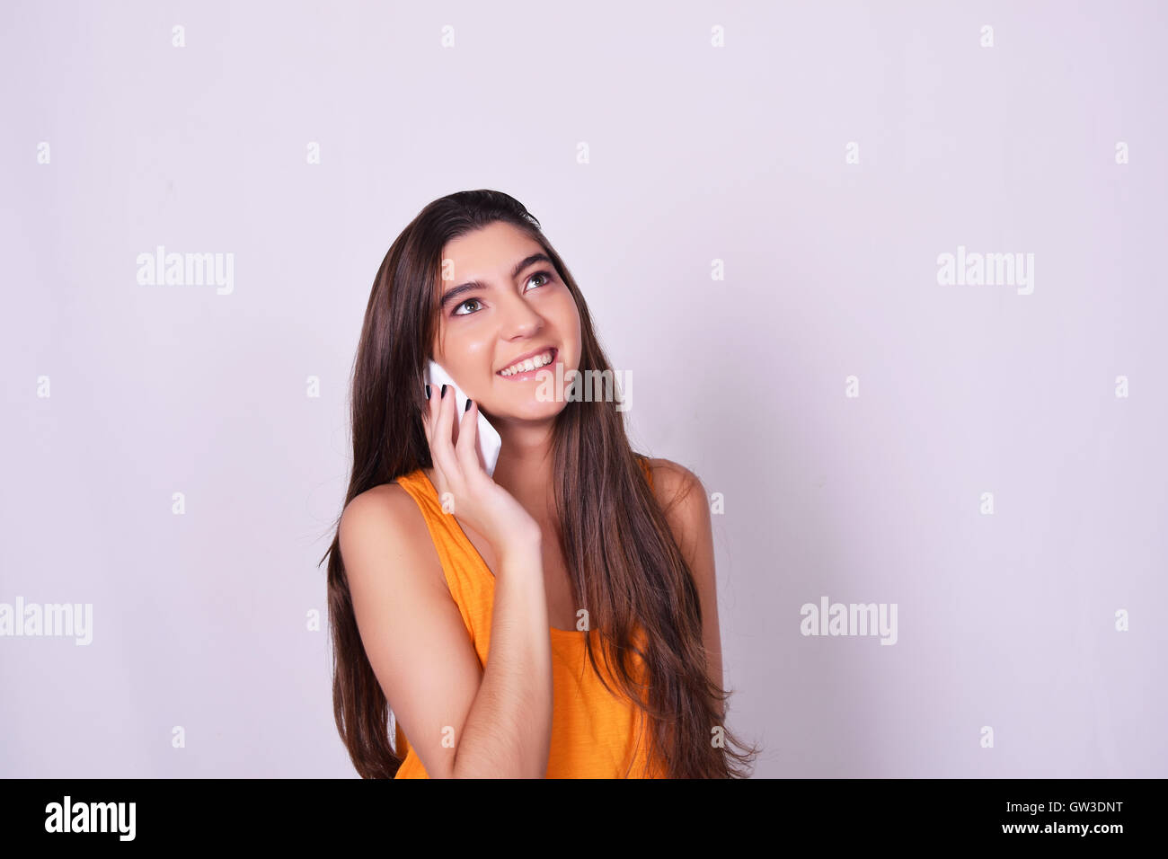 Ritratto di ispanici / caucasian giovane donna utilizzando un telefono cellulare. Donna che parla al telefono, isolate su brackground grigio. Foto Stock