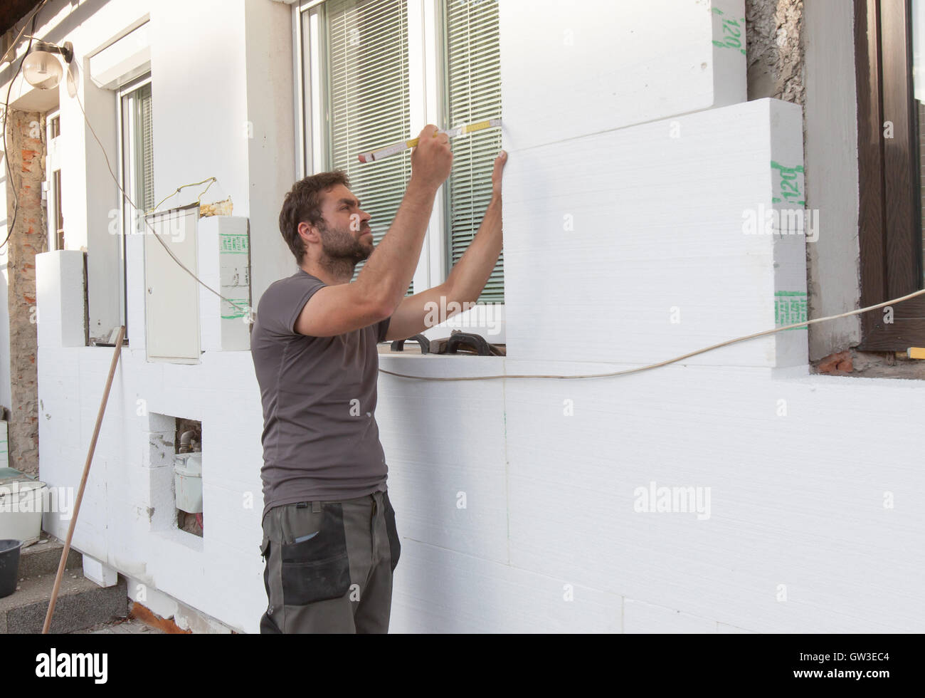 Uomo che lavora con il misuratore di isolamento termico della facciata. Foto Stock