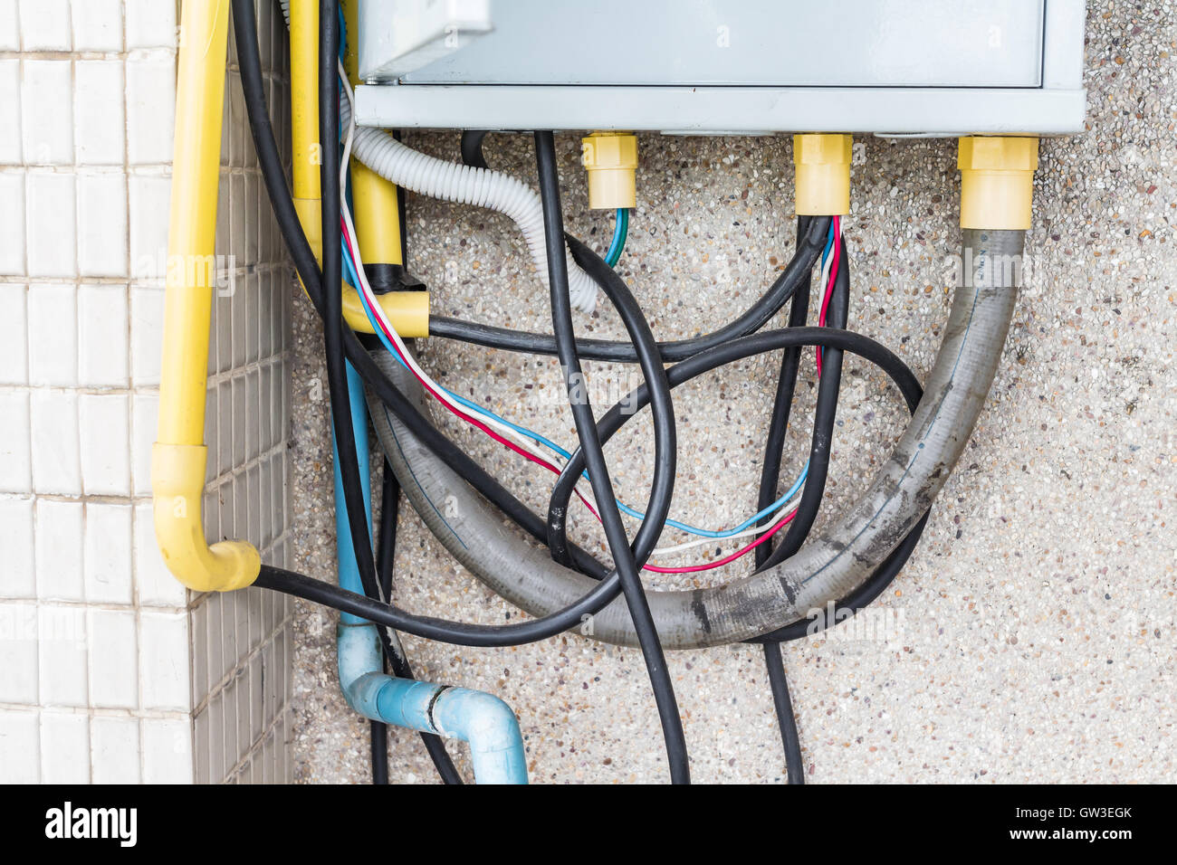 Troppi i connettori maschio per cavo in una presa a muro di mattoni. Pericolo di uso eccessivo di energia elettrica. Foto Stock