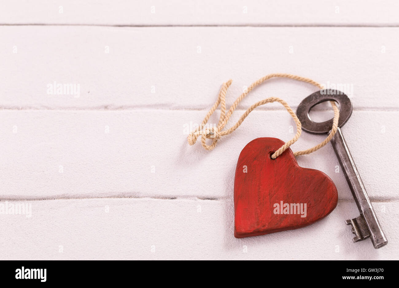 Vecchia chiave con un cuore in legno di colore bianco Foto Stock