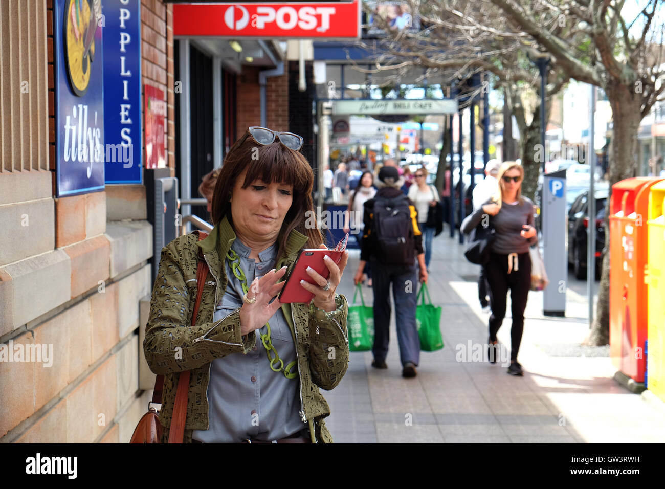 Le donne che utilizzano il telefono cellulare e ATM a Banca di accesso Foto Stock