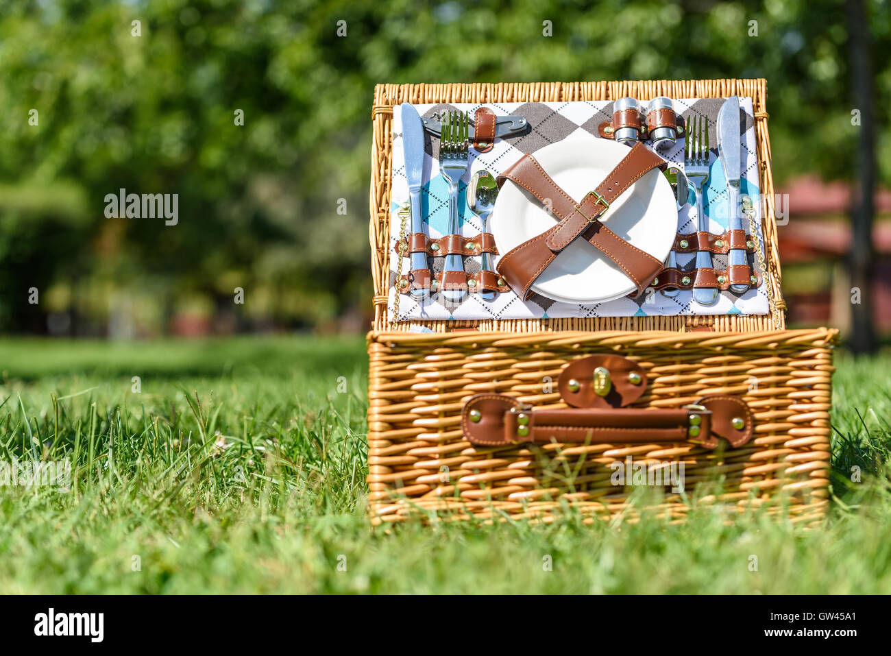 Aperto Cesto picnic con posate in primavera erba verde Foto Stock