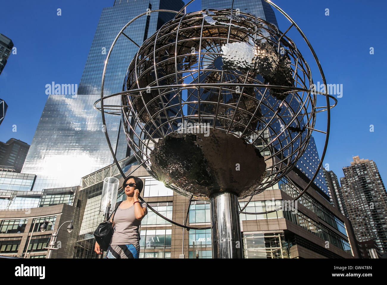 Una donna è a piedi dal metallo globo a Columbus Circle a New York City. Foto Stock