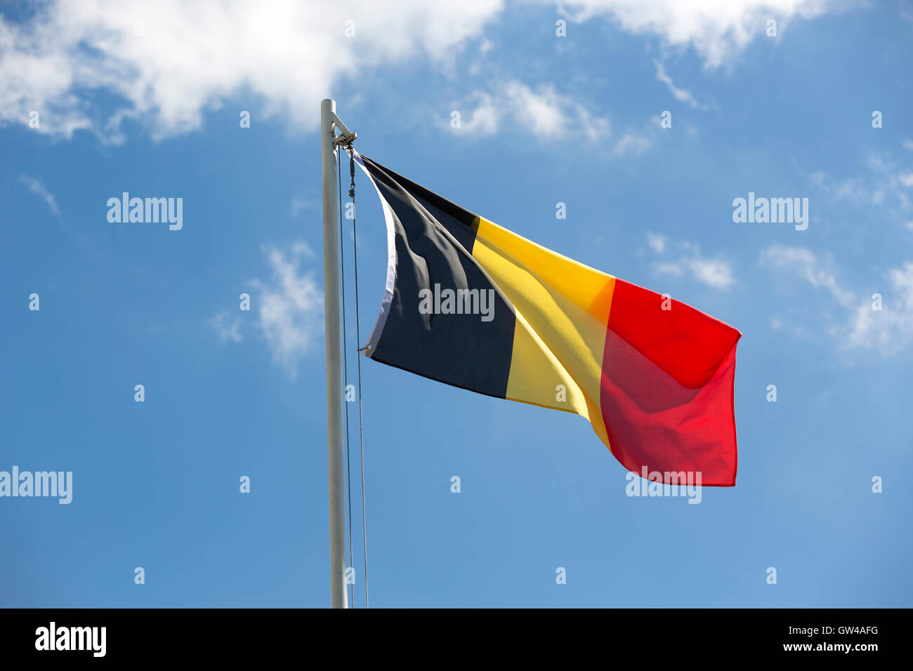 Bandiera nazionale di Belgio su un pennone di fronte blu cielo Foto Stock