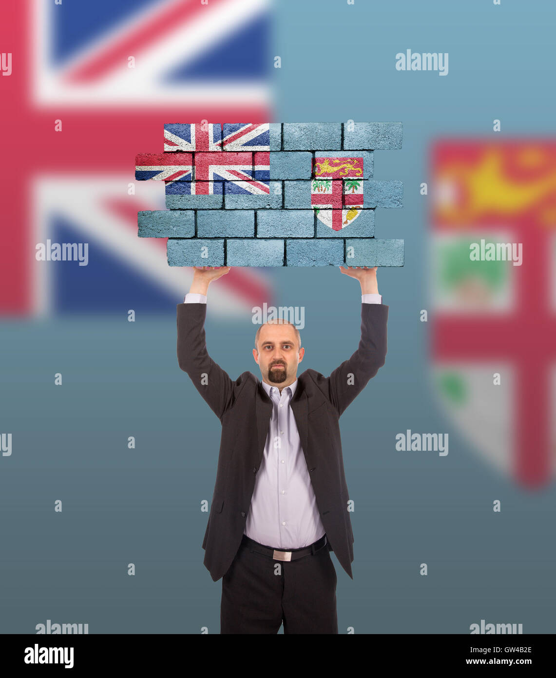 Imprenditore tenendo un grande pezzo di un muro di mattoni Foto Stock