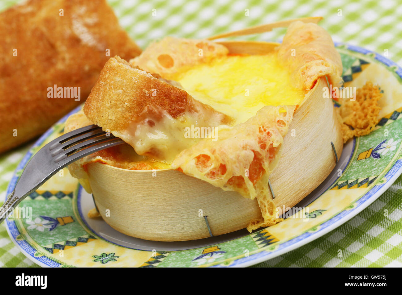 Pezzo di pane francese immersi nel formaggio cotto al forno, close up Foto Stock