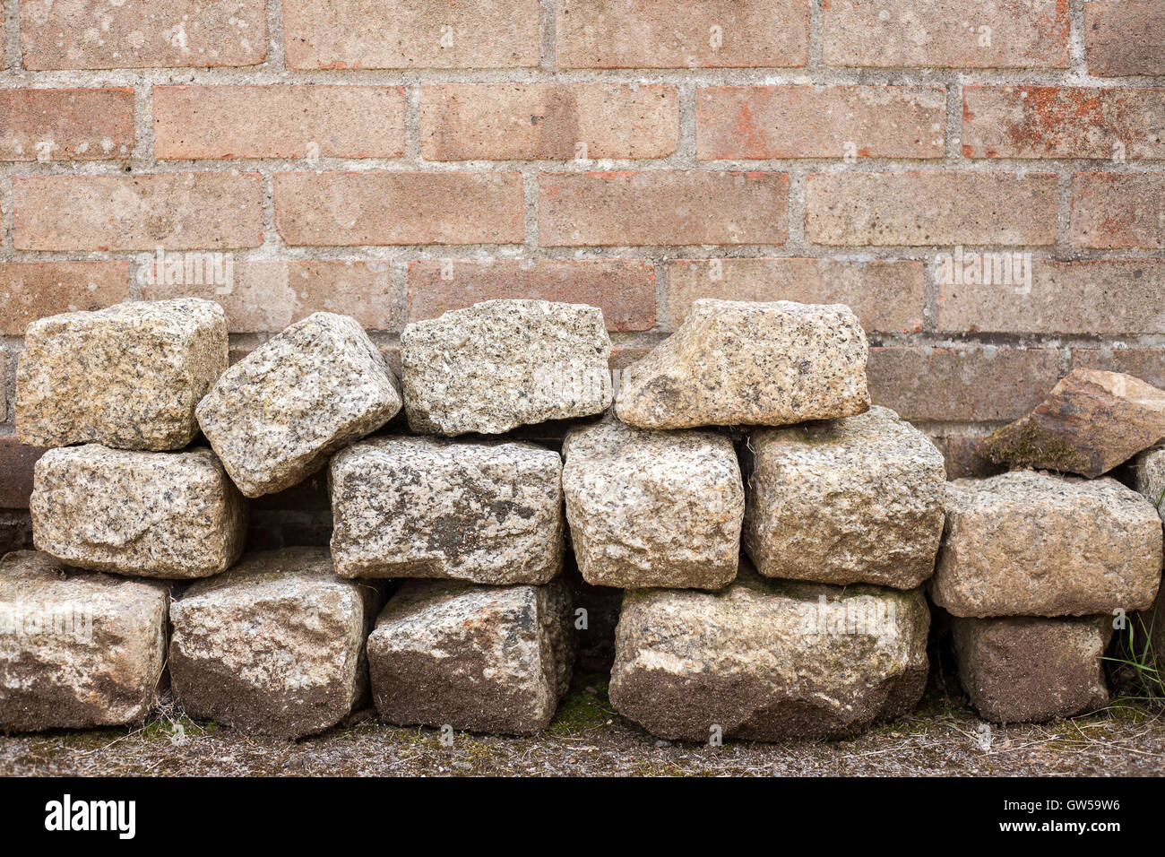 Pila di blocchi di granito di fronte red muro di mattoni Foto Stock
