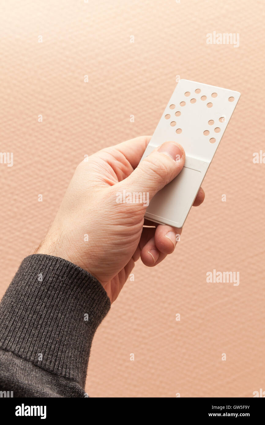 Maschio a mano in plastica trattiene la chiave della porta di carta con fori codice di combinazione Foto Stock