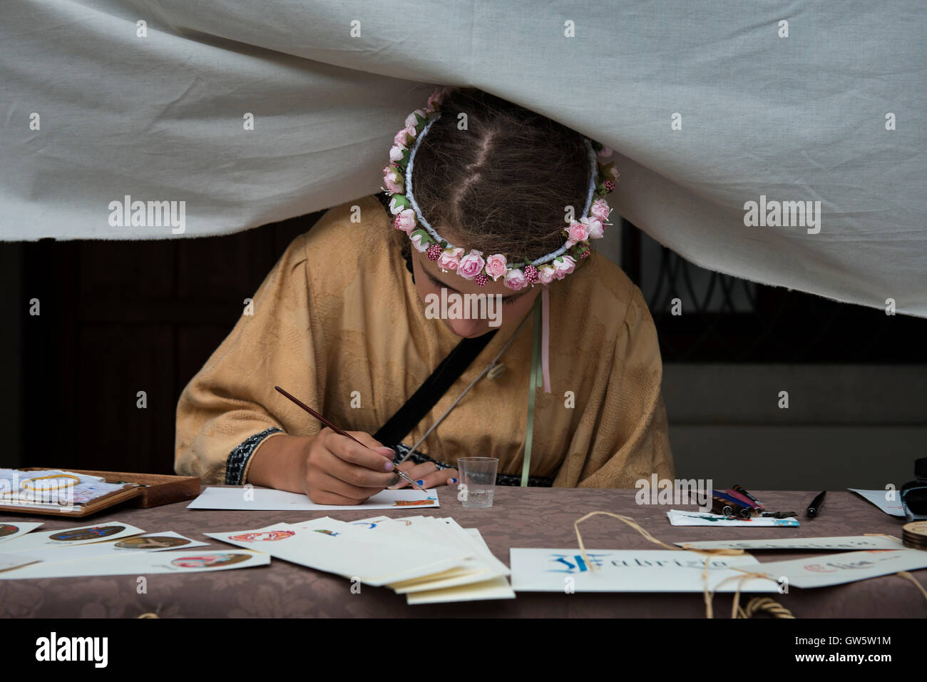 Una ragazza alla festa medievale 'Macia' a Spilimbergo illustra le luminarie e scrive i manoscritti come i tradizionali gli scribi. Foto Stock
