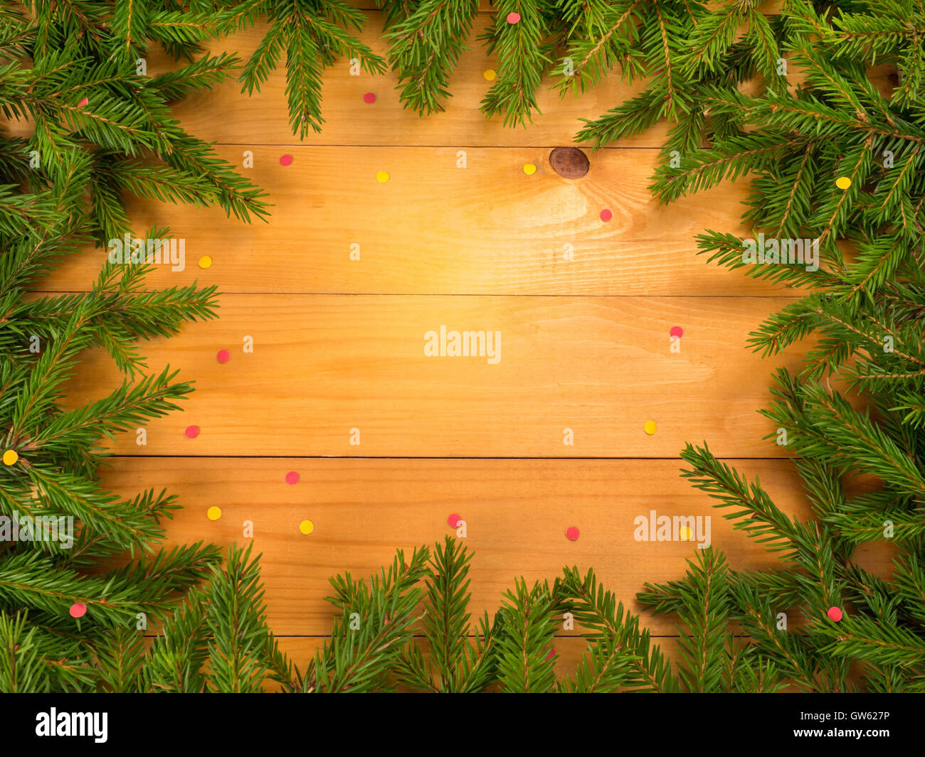 Albero di natale di telaio di rami su assi di legno cosparse di sfondo con colore rosso e giallo coriandoli Foto Stock