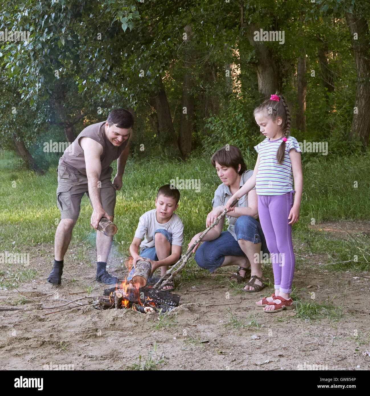 Persone campeggio in foresta, famiglia attiva in natura, Kindle fuoco, durante la stagione estiva Foto Stock
