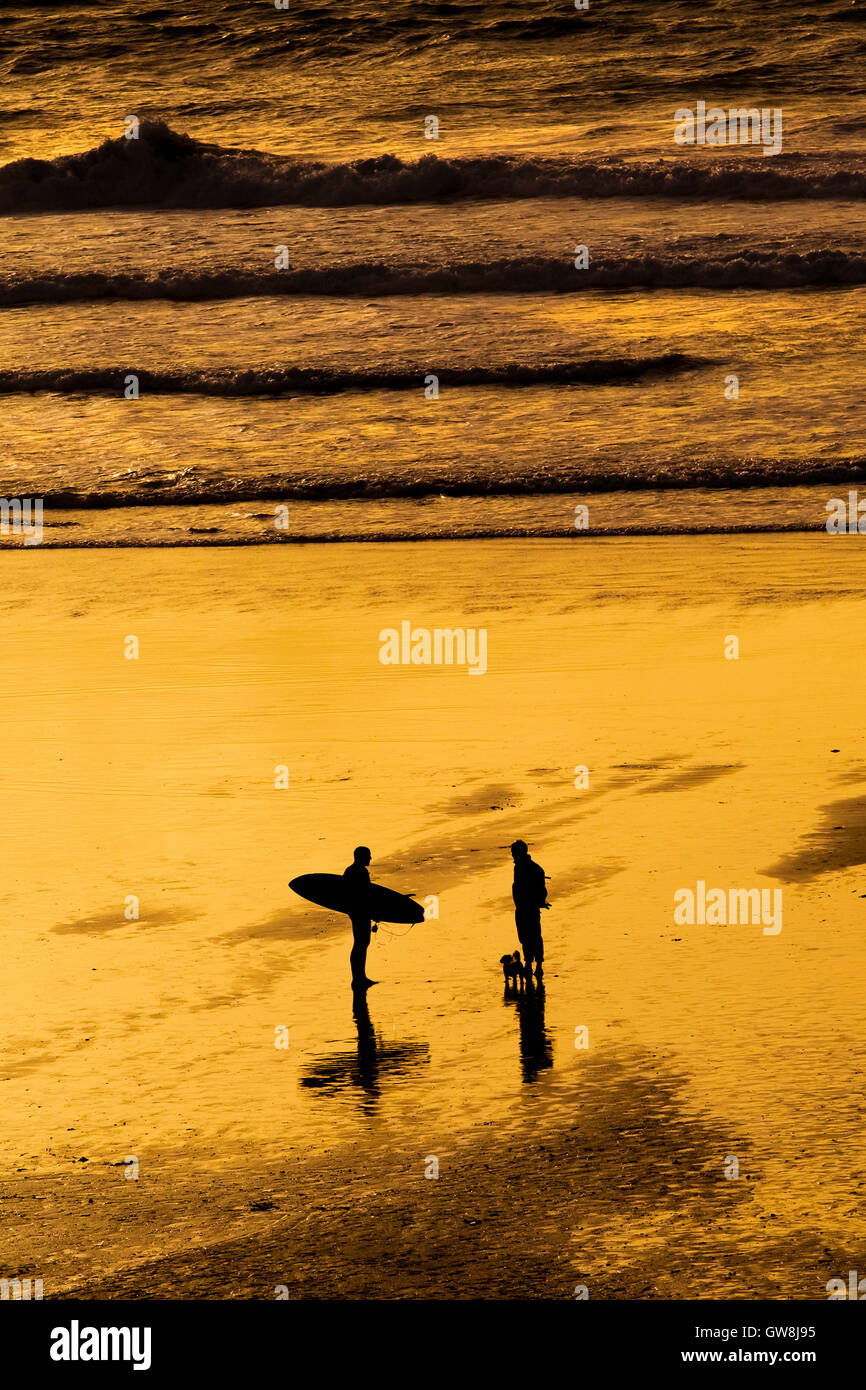 La gente vede in silhouette durante un intenso tramonto. Fistral. La Cornovaglia. Foto Stock