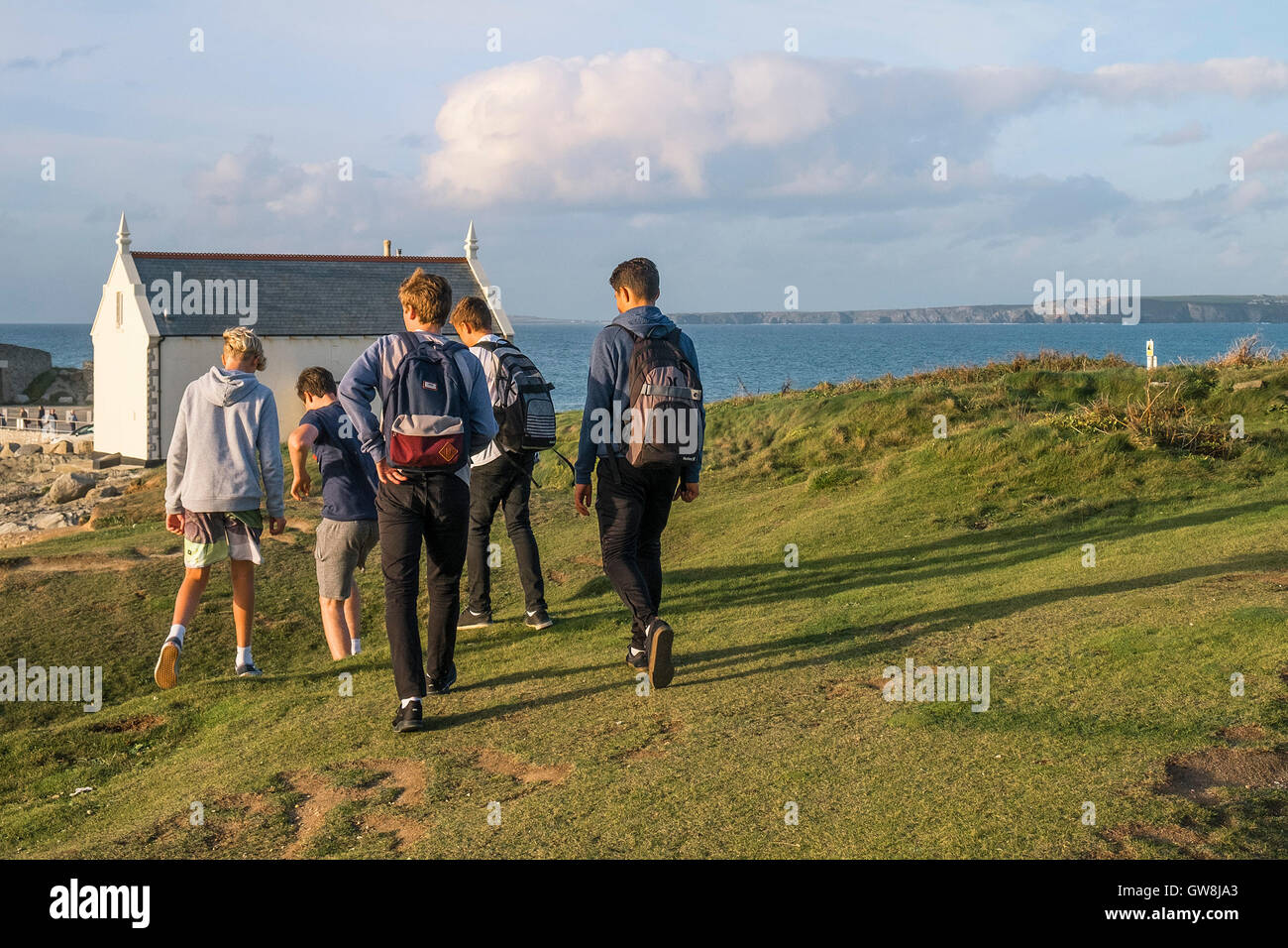 Fiver ragazzi adolescenti a piedi verso Towan in testa, Newquay Cornwall. Foto Stock