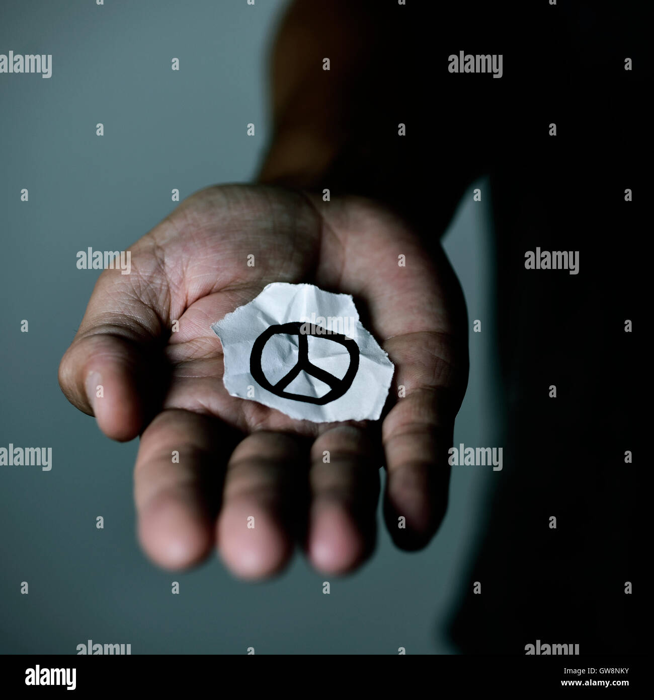 Primo piano di un giovane uomo con un pezzo di carta con un simbolo di pace tracciata in essa, nel palmo della mano Foto Stock