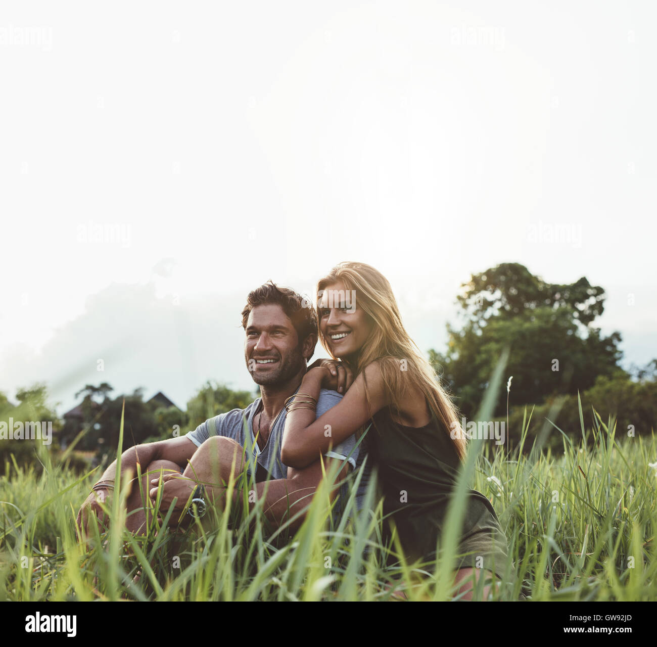 Amorevole coppia giovane seduto sul campo in erba. L uomo e la donna godendo momento romantico all'aperto nel prato. Foto Stock
