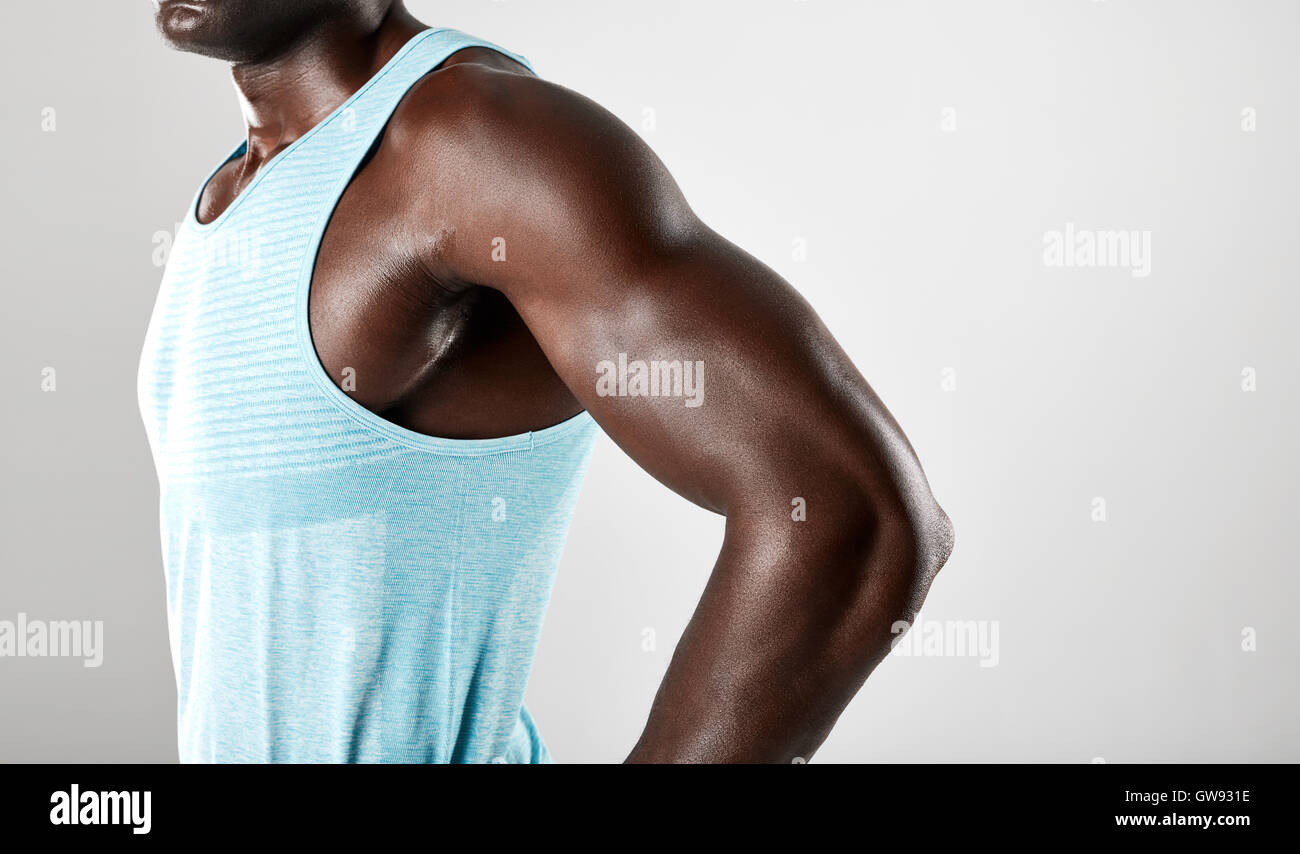 Ritagliato colpo di giovane africano bracci muscolare contro uno sfondo grigio. Foto Stock