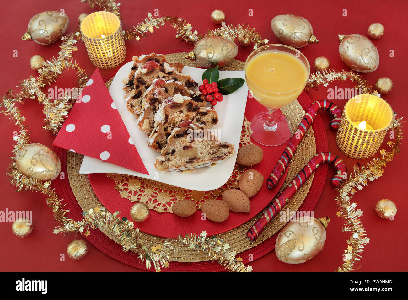 Gastronomia natalizia ancora in vita con lo Stollen fette di torta, zabaione, agrifoglio, fir, oro ninnolo decorazioni e la lamina di cioccolatini incartati. Foto Stock