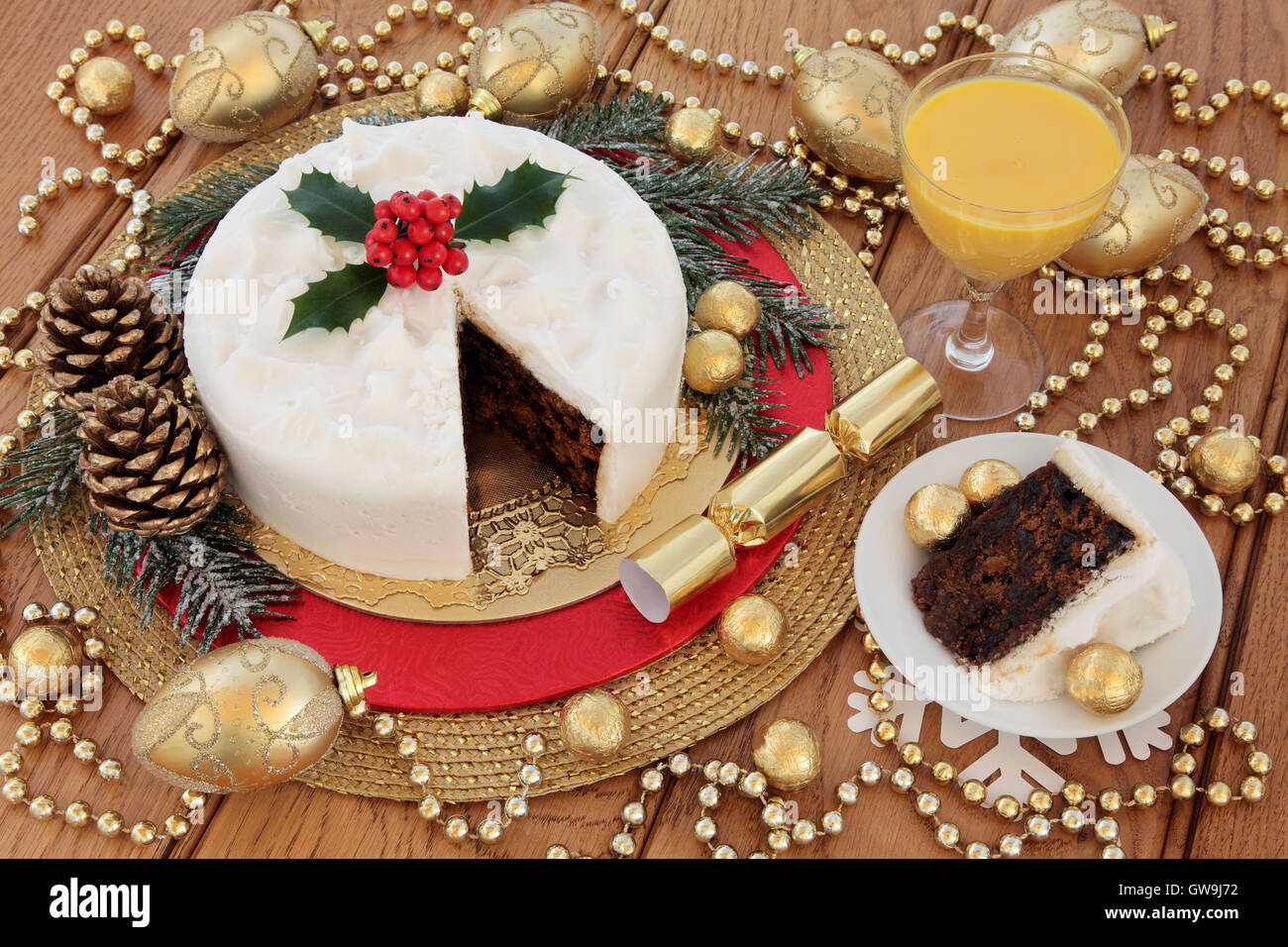 Tradizionale dolce di Natale e slice con holly, coperta di neve in inverno verde, zabaione, oro ninnolo decorazioni e stagnola avvolto Foto Stock