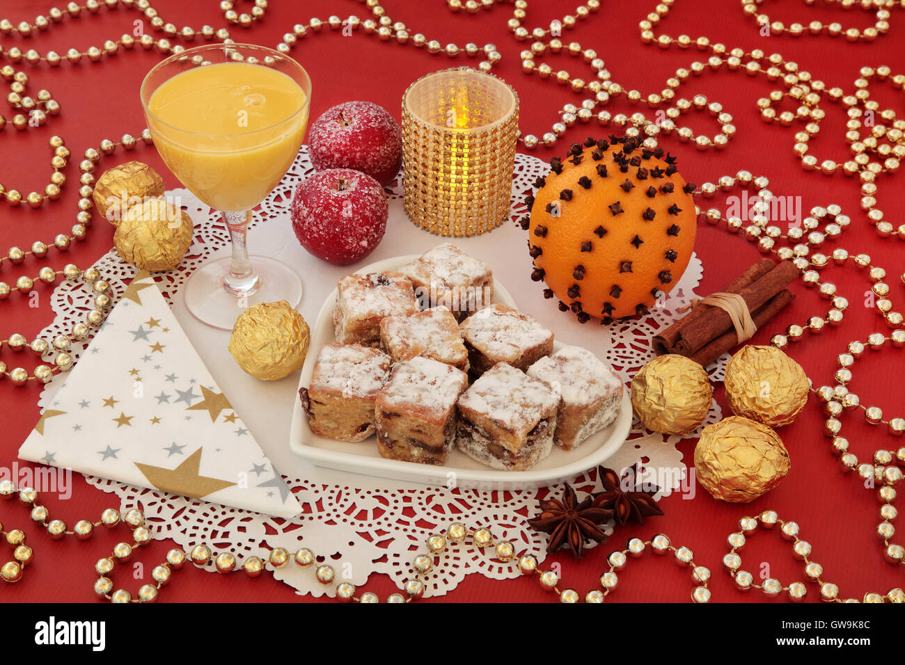 Natale ancora in vita con lo Stollen morde la torta su un cuore piastra sagomata, uovo nog, foglia d'oro di cioccolatini incartati e spezie. Foto Stock