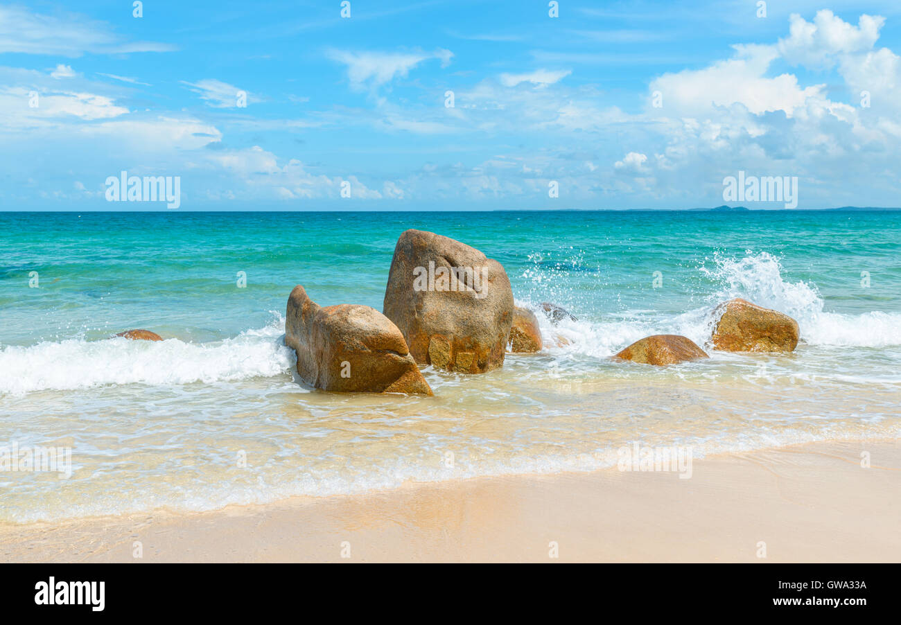 Il mare azzurro chiaro che si infrangono sulle rocce sulla spiaggia sabbiosa tropicale Foto Stock