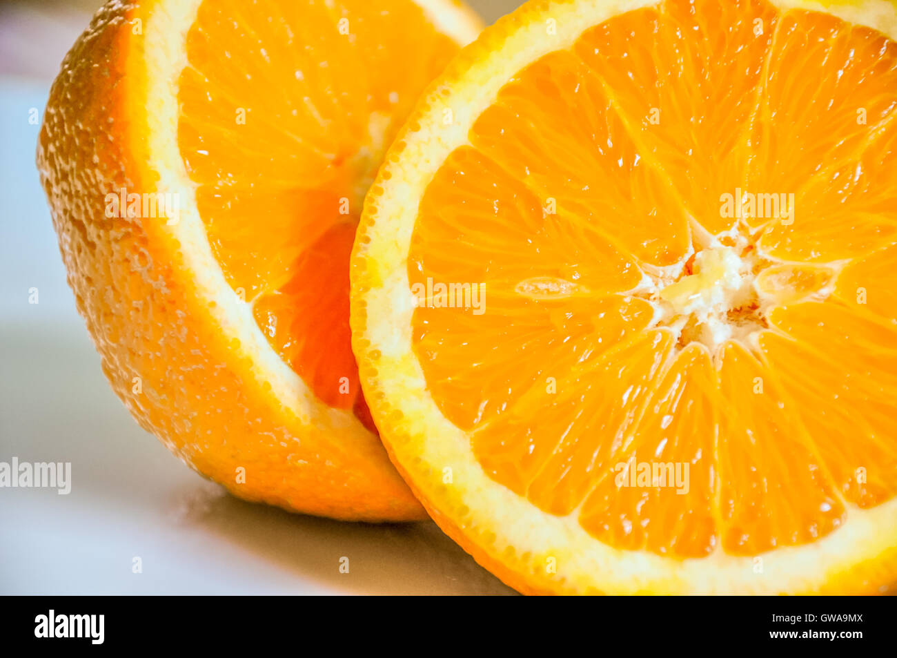 Macro shot di fettine di arancio su una piastra bianca con un colorato tablecover Foto Stock