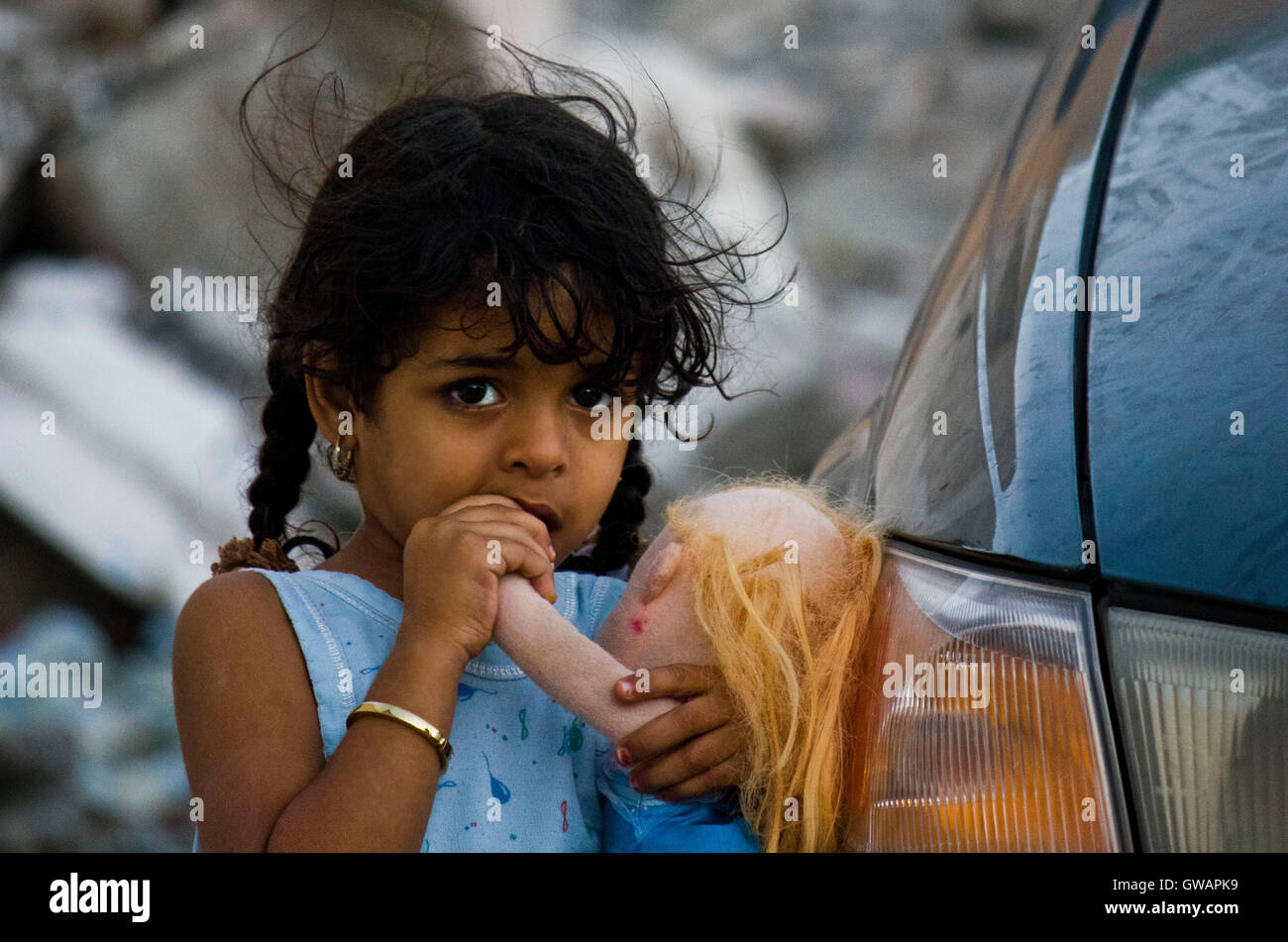 Sur, Oman, Ottobre 22, 2013: Poco omani ragazza in piedi su una vettura in possesso di una bambola, mi sta guardando nella telecamera Foto Stock