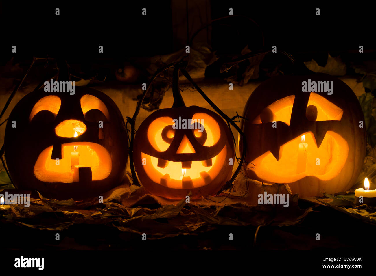 Composizione della foto da tre zucche di Halloween. Il pianto, mad e la paura di qualche zucca contro una vecchia finestra, foglie e può Foto Stock