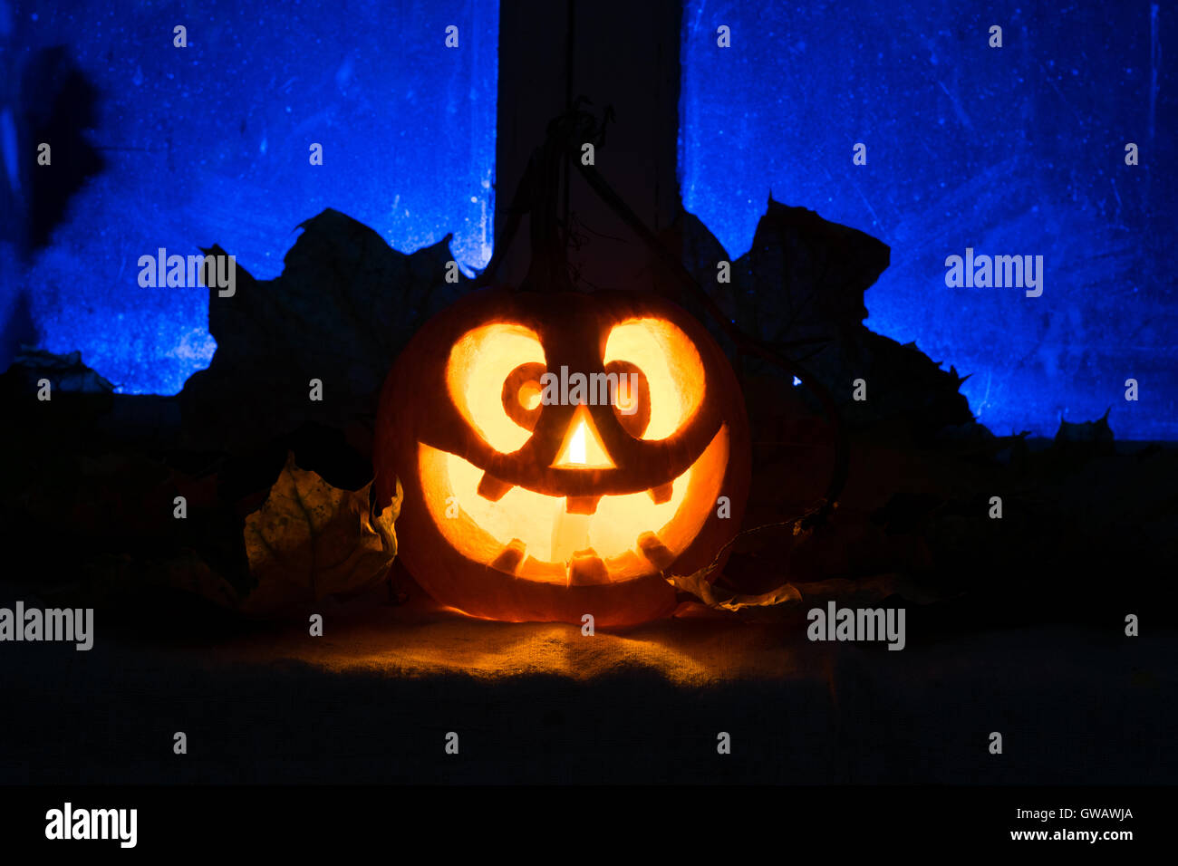 Foto di una festa di Halloween, mad zucca contro una vecchia finestra con foglie di autunno Foto Stock