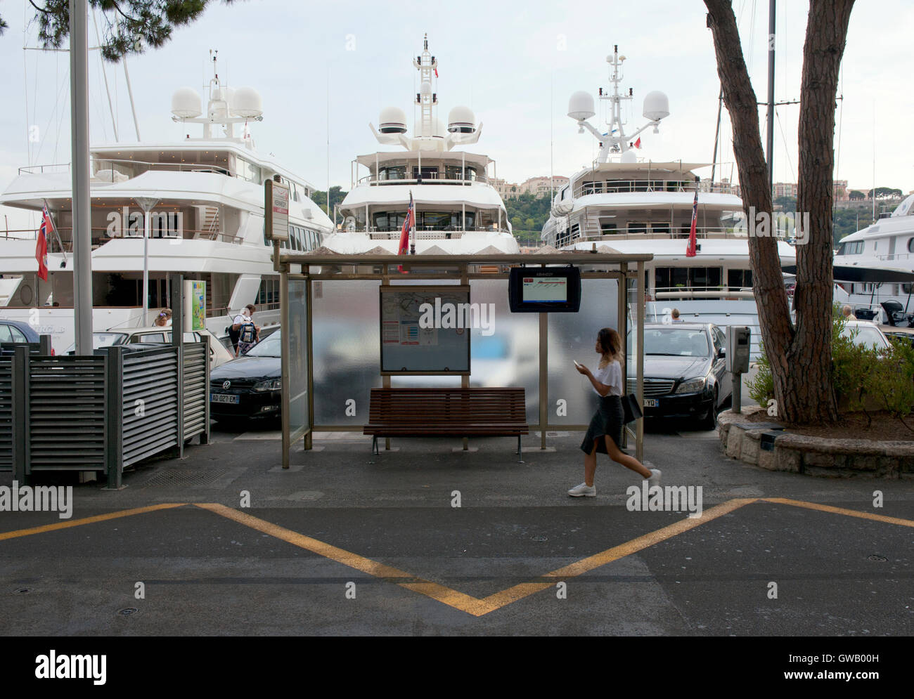 Costoso yacht ormeggiati a Monte Carlo accanto a una fermata bus shelter Foto Stock