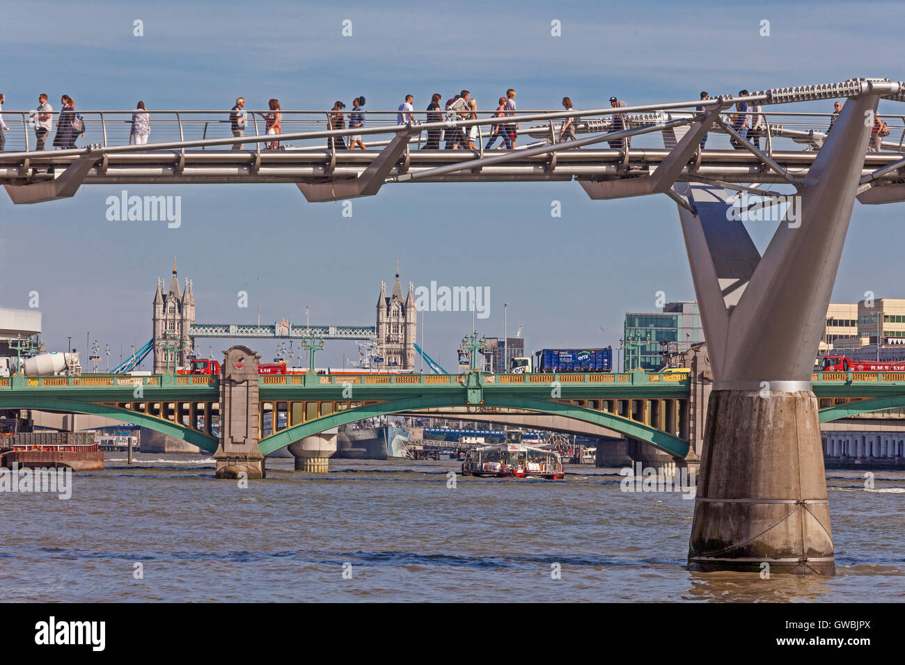 Pedoni che attraversano London Millenium Bridge, con Southwark e la torre di ponti più a valle Foto Stock