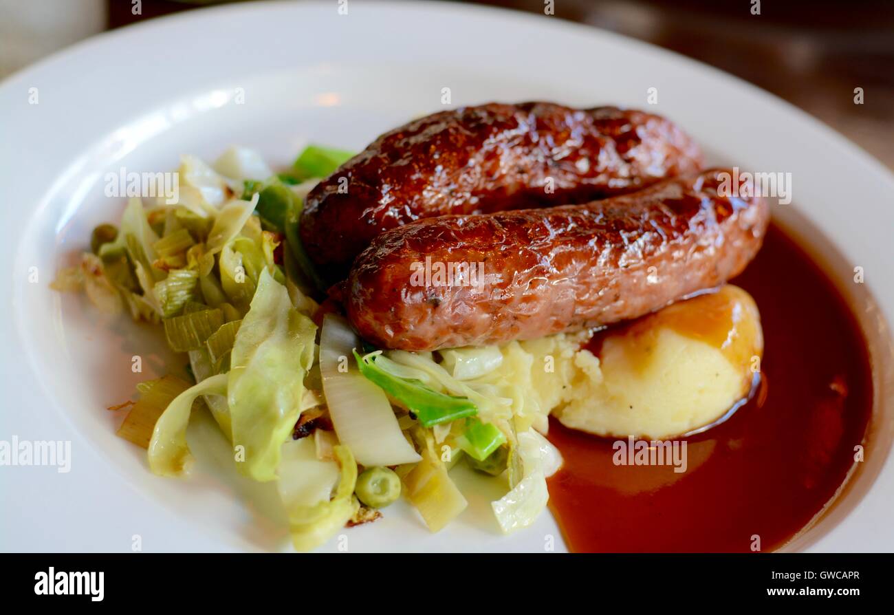 Salsicce e purè di patate e verdure di stagione servita con il vino rosso con sugo di carne su una piastra bianca - filtro applicato Foto Stock