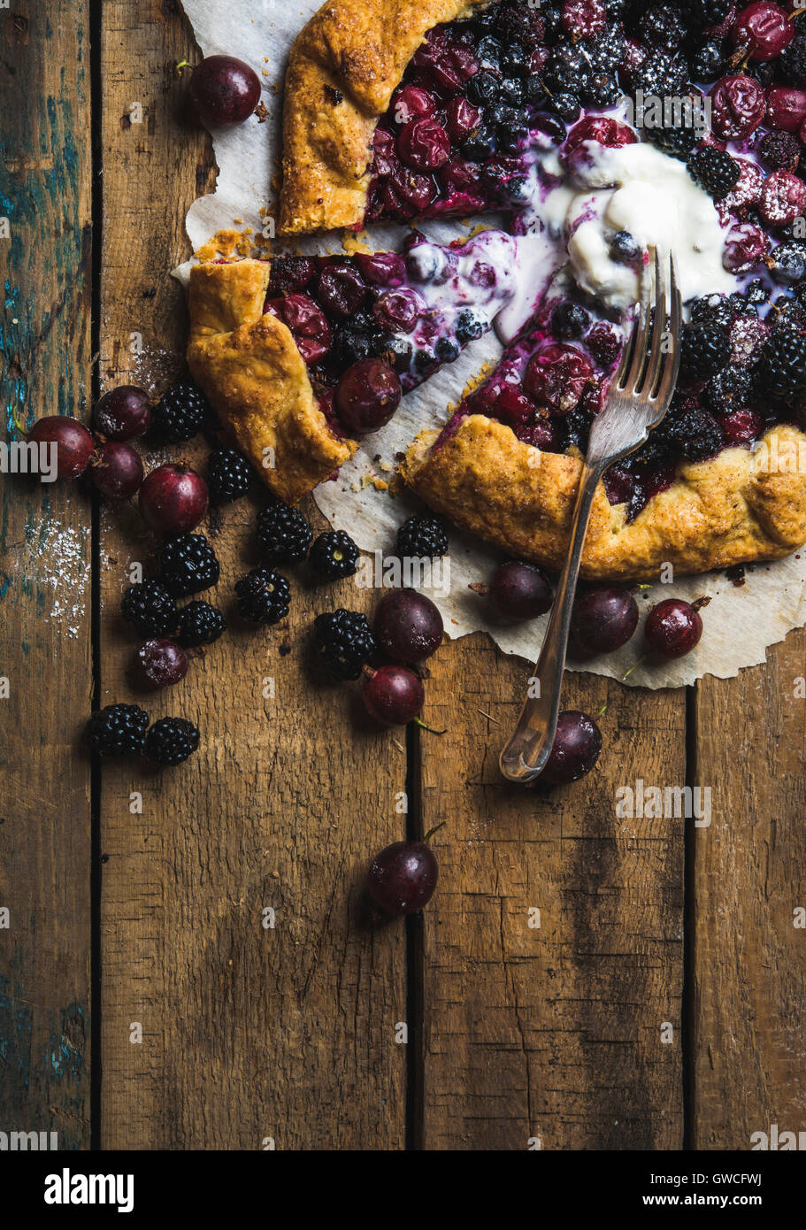 In casa giardino berry galetta o crostata Torta dolce con fuso con gelato alla vaniglia scoop servita con frutti di bosco freschi in legno rustico Foto Stock